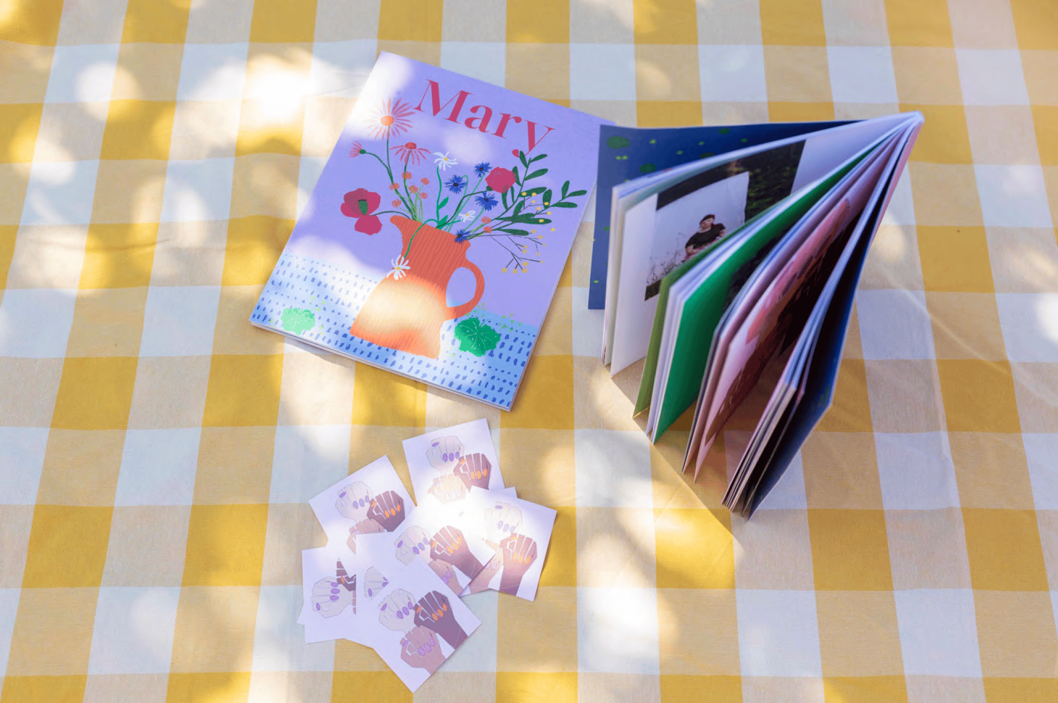 Zeitschrift, Postkarten und Sticker auf gelber Picknickdecke platziert